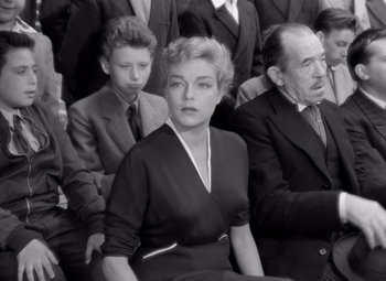 Movie still from “Diabolique” (1955), directed by Henri-Georges Clouzot – An older woman sitting in front of a group of men; Medium shot, High angle