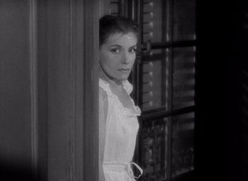 Movie still from “Diabolique” (1955), directed by Henri-Georges Clouzot – A black and white photo of a woman looking out of a window; Medium shot, High angle