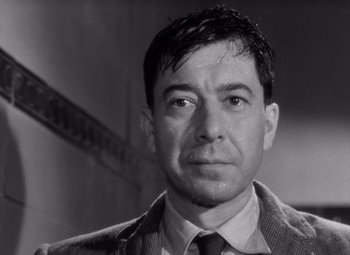 Movie still from “Diabolique” (1955), directed by Henri-Georges Clouzot – Black and white photograph of a man in a suit and tie; Close Up shot, Low angle