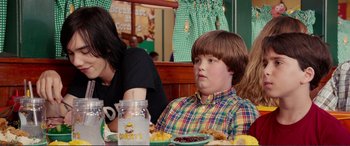 Movie still from “Diary of a Wimpy Kid: The Long Haul” (2017), directed by David Bowers – A boy sitting at a table in front of food; Medium shot, Over the shoulder angle