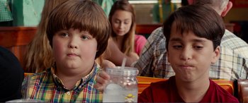 Movie still from “Diary of a Wimpy Kid: The Long Haul” (2017), directed by David Bowers – A young boy sitting at a table in front of a jar; Close Up shot, Over the shoulder angle