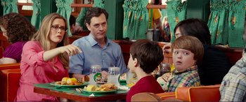 Movie still from “Diary of a Wimpy Kid: The Long Haul” (2017), directed by David Bowers – A man sitting at a table with two children; Medium shot, Over the shoulder angle