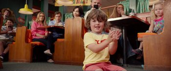 Movie still from “Diary of a Wimpy Kid: The Long Haul” (2017), directed by David Bowers – A little boy clapping his hands in front of a group of people; Medium shot, Over the shoulder angle