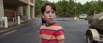 Movie still from “Diary of a Wimpy Kid: The Long Haul” (2017), directed by David Bowers – A young boy in a striped shirt standing in a parking lot; Close Up shot, Over the shoulder angle