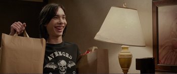 Movie still from “Diary of a Wimpy Kid: The Long Haul” (2017), directed by David Bowers – A man sitting in front of a lamp and smiling; Medium shot, Over the shoulder angle