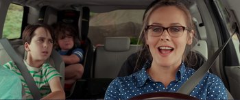 Movie still from “Diary of a Wimpy Kid: The Long Haul” (2017), directed by David Bowers – A woman in a blue polka dot shirt is in the back of a car; Close Up shot, Over the shoulder angle
