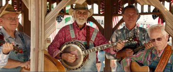 Movie still from “Diary of a Wimpy Kid: The Long Haul” (2017), directed by David Bowers – An older man playing a banjo in front of an audience; Medium shot, High angle