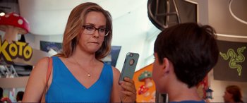 Movie still from “Diary of a Wimpy Kid: The Long Haul” (2017), directed by David Bowers – A woman holding a cell phone in front of a boy; Close Up shot, Over the shoulder angle