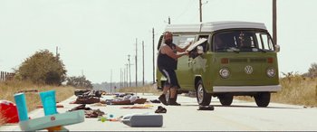 Movie still from “Diary of a Wimpy Kid: The Long Haul” (2017), directed by David Bowers – A man standing in front of a van on the side of the road; Wide shot, Low angle