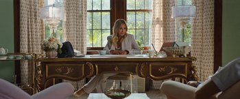 Movie still from “Do Revenge” (2022), directed by Jennifer Kaytin Robinson – A woman sitting at a table in front of a window; Medium shot, Over the shoulder angle