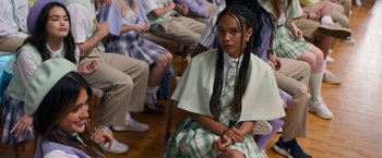 Movie still from “Do Revenge” (2022), directed by Jennifer Kaytin Robinson – A woman sitting on the floor in front of a group of people; Medium shot, High angle