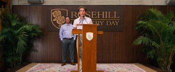 Movie still from “Do Revenge” (2022), directed by Jennifer Kaytin Robinson – A man standing at a podium speaking to a crowd; Medium shot, Low angle