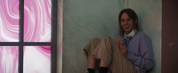 Movie still from “Do Revenge” (2022), directed by Jennifer Kaytin Robinson – A woman sitting on the ground in front of a green wall; Medium shot, High angle