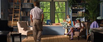 Movie still from “Do Revenge” (2022), directed by Jennifer Kaytin Robinson – A man and a woman sitting on a couch in front of a window; Wide shot, Over the shoulder angle