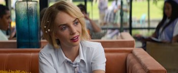 Movie still from “Do Revenge” (2022), directed by Jennifer Kaytin Robinson – A woman sitting in a booth looking at the camera; Close Up shot, Over the shoulder angle