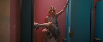 Movie still from “Do Revenge” (2022), directed by Jennifer Kaytin Robinson – A woman sitting on a toilet in a pink room; Medium shot, High angle