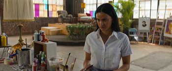Movie still from “Do Revenge” (2022), directed by Jennifer Kaytin Robinson – A woman standing in front of a table with paint brushes on top of it; Medium shot, Over the shoulder angle