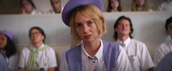 Movie still from “Do Revenge” (2022), directed by Jennifer Kaytin Robinson – A woman in a purple hat and a tie; Close Up shot, Over the shoulder angle