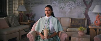 Movie still from “Do Revenge” (2022), directed by Jennifer Kaytin Robinson – A woman sitting in a chair holding a drink; Medium shot, High angle