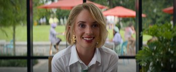 Movie still from “Do Revenge” (2022), directed by Jennifer Kaytin Robinson – A woman in a white shirt and a green tie smiling; Close Up shot, Over the shoulder angle