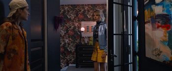 Movie still from “Do Revenge” (2022), directed by Jennifer Kaytin Robinson – A woman standing in front of a mirror in a room with floral wallpaper; Medium shot, Over the shoulder angle