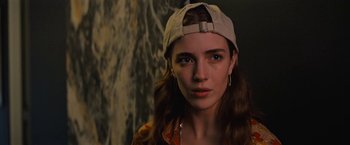 Movie still from “Do Revenge” (2022), directed by Jennifer Kaytin Robinson – A woman wearing a baseball cap and a yellow jacket; Close Up shot, Low angle
