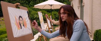 Movie still from “Do Revenge” (2022), directed by Jennifer Kaytin Robinson – A woman is painting a picture on canvas outside; Medium shot, Over the shoulder angle