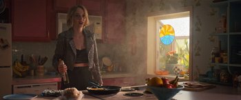 Movie still from “Do Revenge” (2022), directed by Jennifer Kaytin Robinson – A woman standing at a table with a bowl of fruit; Medium shot, Over the shoulder angle