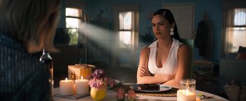 Movie still from “Do Revenge” (2022), directed by Jennifer Kaytin Robinson – A woman sitting at a dinner table with a candle; Medium shot, Over the shoulder angle