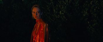 Movie still from “Do Revenge” (2022), directed by Jennifer Kaytin Robinson – A woman in a red jacket standing in front of a tree; Close Up shot, Over the shoulder angle