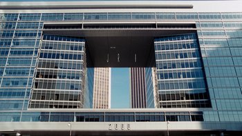 Movie still from “Dinner for Schmucks” (2010), directed by Jay Roach – A large building with many windows on a sunny day; Extreme Wide shot, High angle
