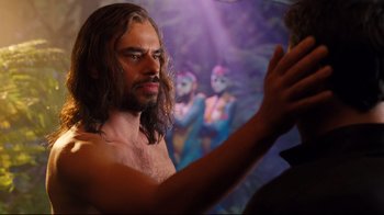 Movie still from “Dinner for Schmucks” (2010), directed by Jay Roach – A man with long brown hair and no shirt is holding his hands up; Close Up shot, Over the shoulder angle
