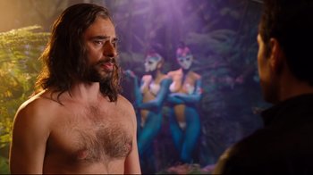 Movie still from “Dinner for Schmucks” (2010), directed by Jay Roach – A man with a hairy chest standing in front of a painting; Medium shot, Over the shoulder angle