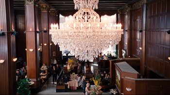 Movie still from “Dinner for Schmucks” (2010), directed by Jay Roach – A large crystal chandelier hangs over a dining room table; Extreme Wide shot, High angle