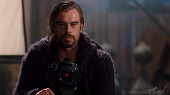 Movie still from “Dinner for Schmucks” (2010), directed by Jay Roach – A man holding a camera while wearing a sweater; Close Up shot, Over the shoulder angle