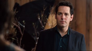 Movie still from “Dinner for Schmucks” (2010), directed by Jay Roach – A man in a black suit and a green shirt; Close Up shot, Over the shoulder angle