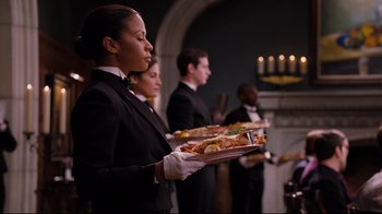 Waitresses holding trays of food in front of candles