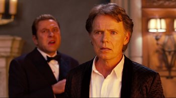 Movie still from “Dinner for Schmucks” (2010), directed by Jay Roach – A man in a suit and tie standing next to another man in a tuxedo; Close Up shot, Over the shoulder angle
