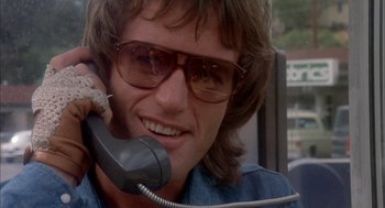 Movie still from “Dirty Mary Crazy Larry” (1974), directed by John Hough – A man talking on a phone while wearing sunglasses; Close Up shot, Low angle