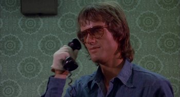 Movie still from “Dirty Mary Crazy Larry” (1974), directed by John Hough – A man with glasses is talking on a phone; Close Up shot, Low angle
