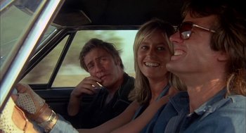 Movie still from “Dirty Mary Crazy Larry” (1974), directed by John Hough – A group of people sitting in the back seat of a car; Medium shot, Low angle