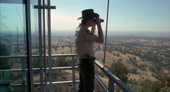 Movie still from “Dirty Mary Crazy Larry” (1974), directed by John Hough – A man that is looking through binoculars; Wide shot, Low angle