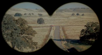 Movie still from “Dirty Mary Crazy Larry” (1974), directed by John Hough – A view of a road through a pair of binoculars; Extreme Wide shot, High angle
