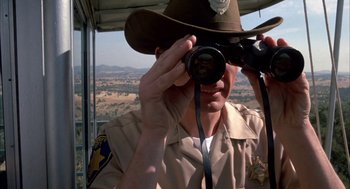 Movie still from “Dirty Mary Crazy Larry” (1974), directed by John Hough – A man in a brown hat taking a picture with a camera; Close Up shot, Low angle