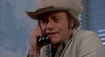 Movie still from “Dirty Mary Crazy Larry” (1974), directed by John Hough – A man in a cowboy hat talking on a phone; Close Up shot, Low angle