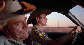 Movie still from “Dirty Mary Crazy Larry” (1974), directed by John Hough – A man in a sheriff's hat driving a car; Close Up shot, Low angle