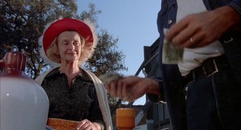 Movie still from “Dirty Mary Crazy Larry” (1974), directed by John Hough – An older woman wearing a red hat is handing money to an older man; Medium shot, Low angle