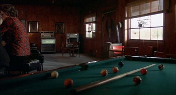 Movie still from “Dirty Mary Crazy Larry” (1974), directed by John Hough – A pool table in a living room with an arcade machine in the background; Wide shot, High angle