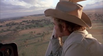 Movie still from “Dirty Mary Crazy Larry” (1974), directed by John Hough – A man wearing a cowboy hat looking out the window of an airplane; Wide shot, Over the shoulder angle