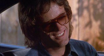 Movie still from “Dirty Mary Crazy Larry” (1974), directed by John Hough – A person wearing glasses and smiling; Close Up shot, Low angle